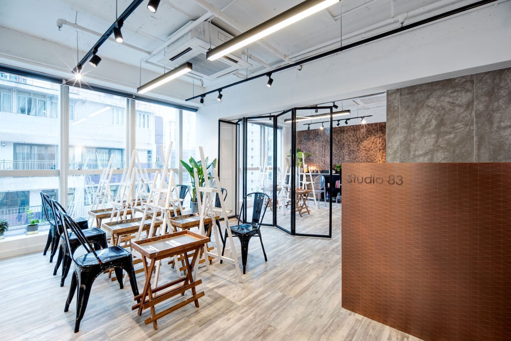 Studio 83 Central Hong Kong art studio with Studio 83 branded copper desk, white easels, and painting class stations for art jamming